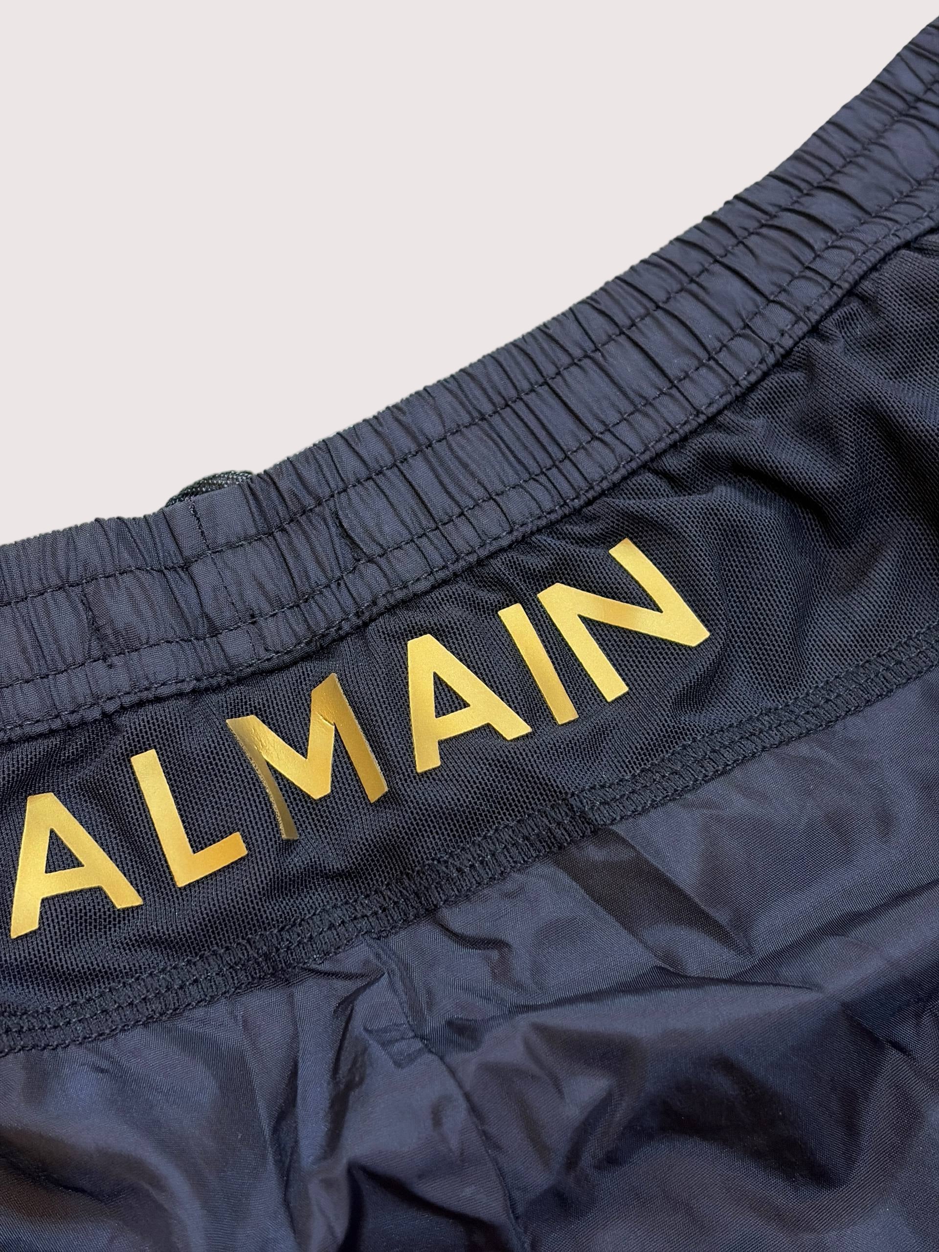 Navy shorts with 'BALMAIN' branding on a beige background
