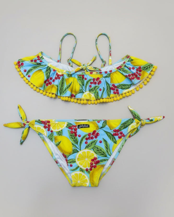 Colorful bikini set with lemon and berry pattern on a beige surface