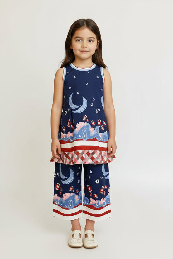 Young girl wearing a sleeveless top and wide-leg pants with a nautical pattern on a plain background